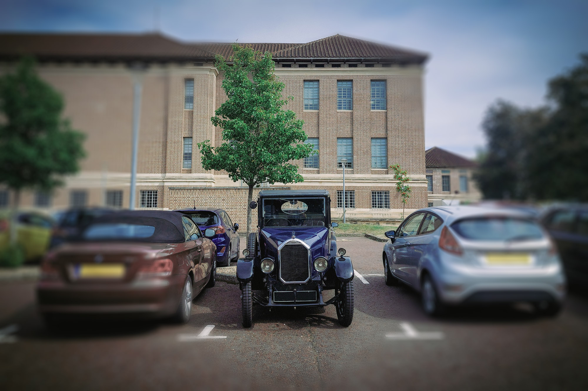 A classic car parked between two modern cars.